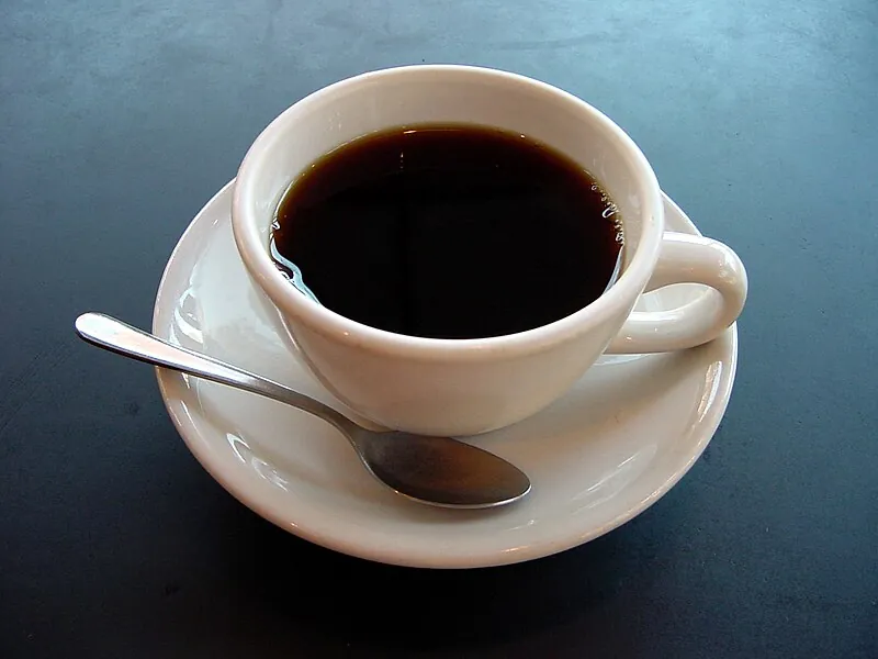 A coffee cup representing a decaffeinated espresso, which typically contains 2 to 12mg of caffeine per shot compared to 60 to 75mg in a regular single espresso, as decaffeination processes are required to remove a minimum of 97% of the caffeine from green coffee beans before roasting, with the Swiss Water Process and CO2 Process achieving the highest caffeine removal rates while preserving the most flavour compounds